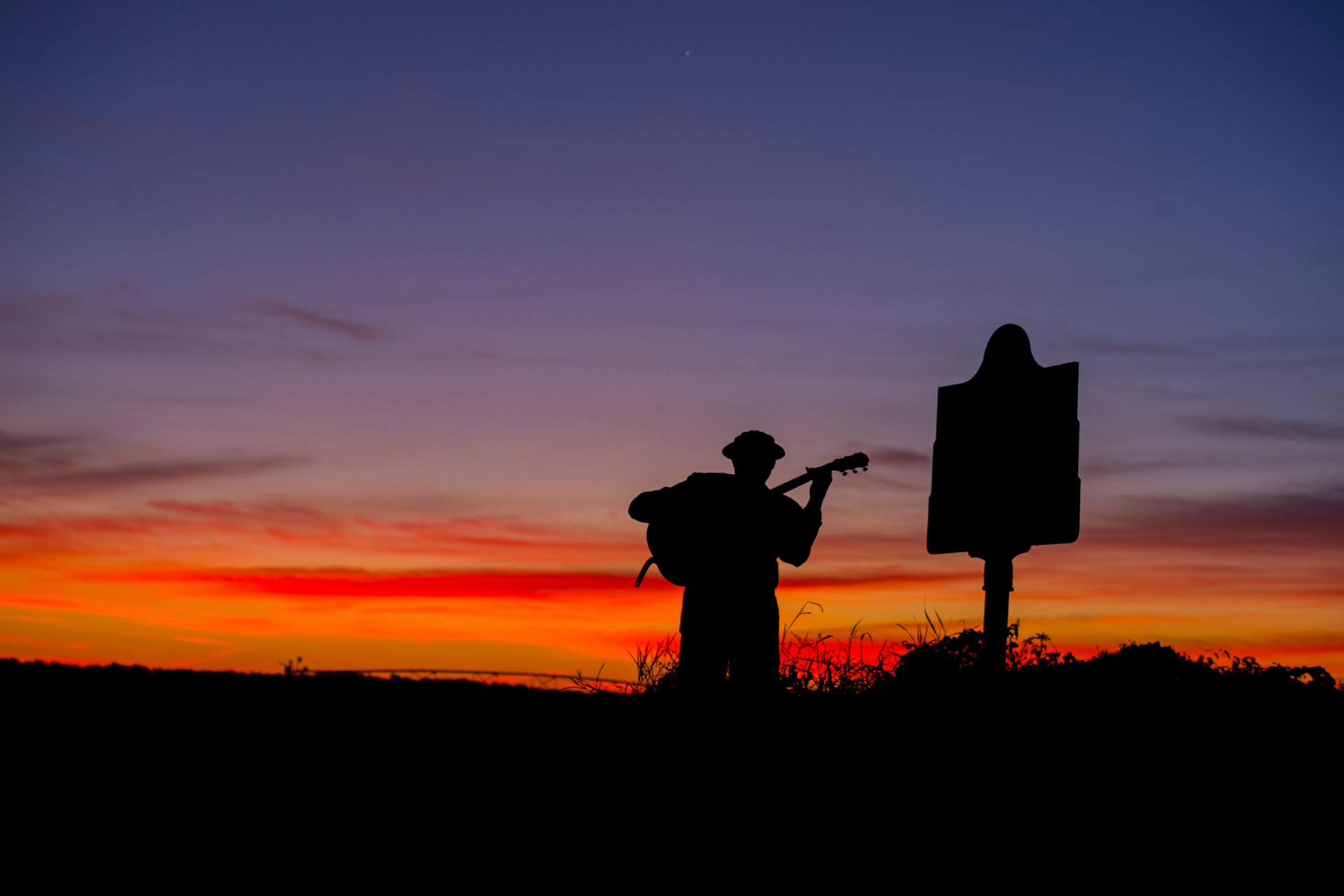 Blues musician silhouetted at sunset along the Mississippi Blues Trail, Greenwood